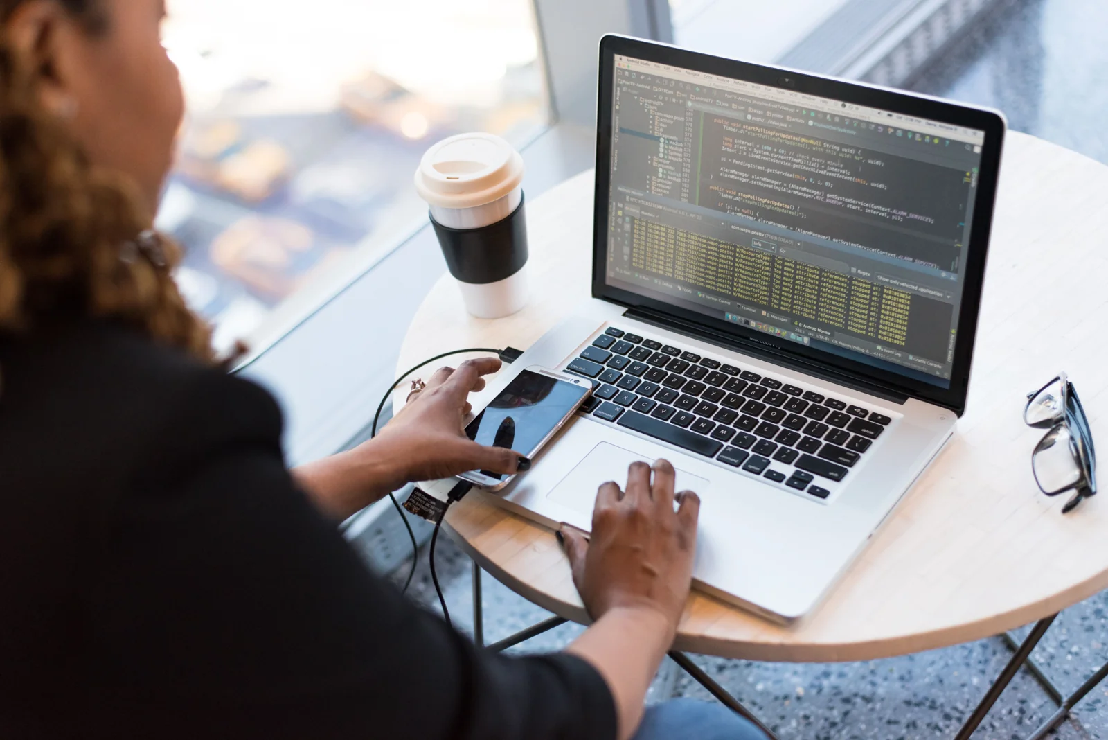 Developer working on a laptop beside a phone and coffee