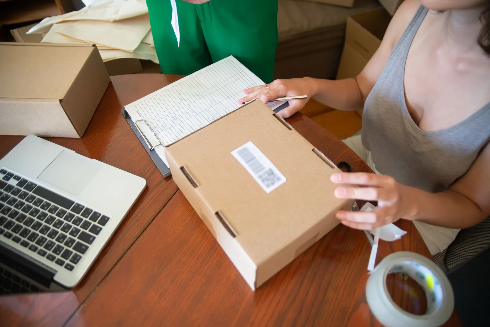 Business owner packing an online order beside a laptop and shipping supplies